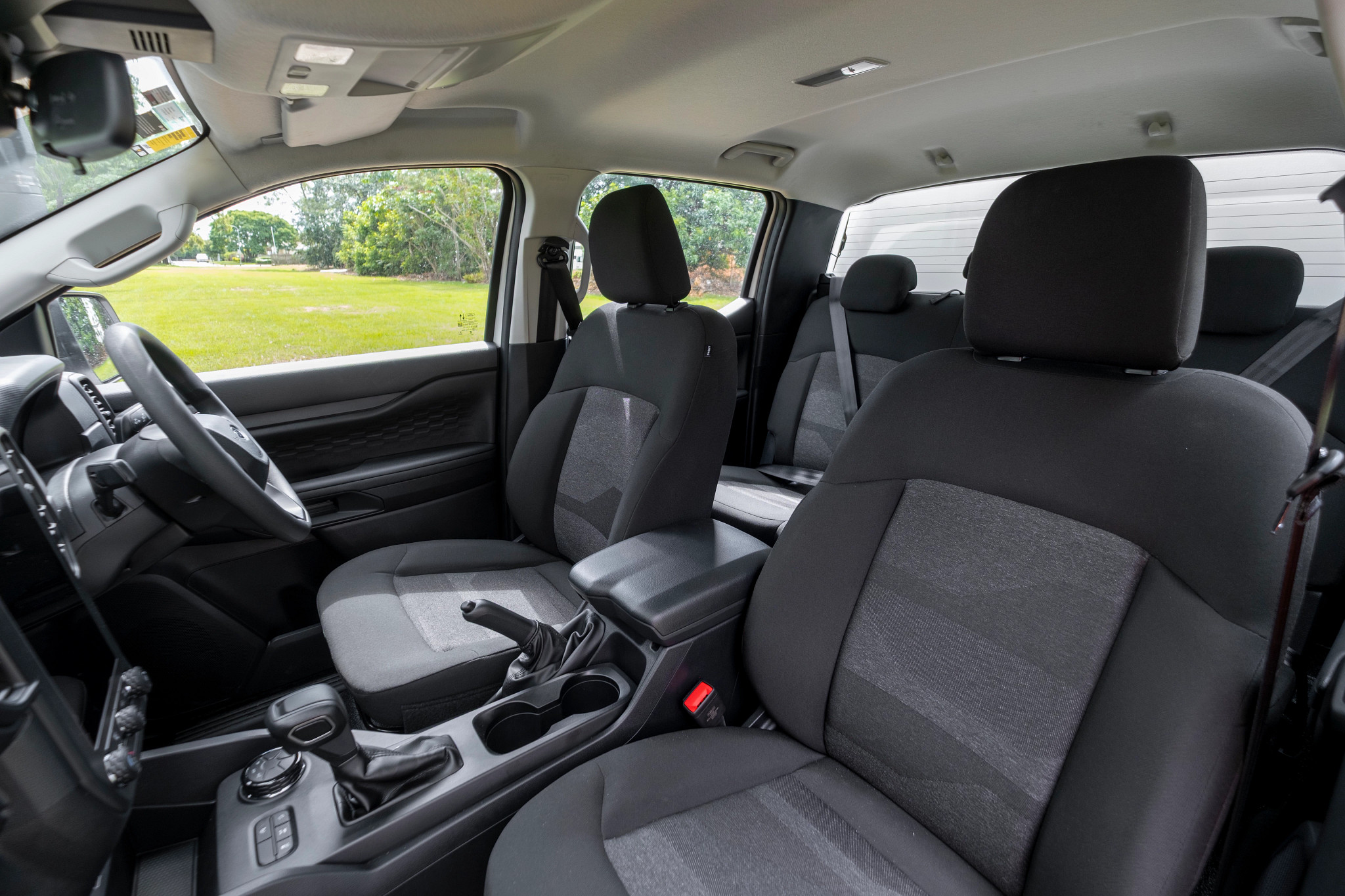 Interior of a modern vehicle with dark grey fabric seats, steering wheel on the left, and centre console.