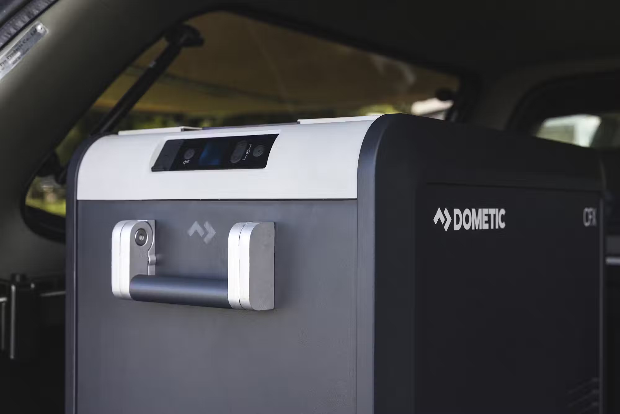 Dometic portable fridge-freezer with a digital display and silver handle inside the back of a campervan.
