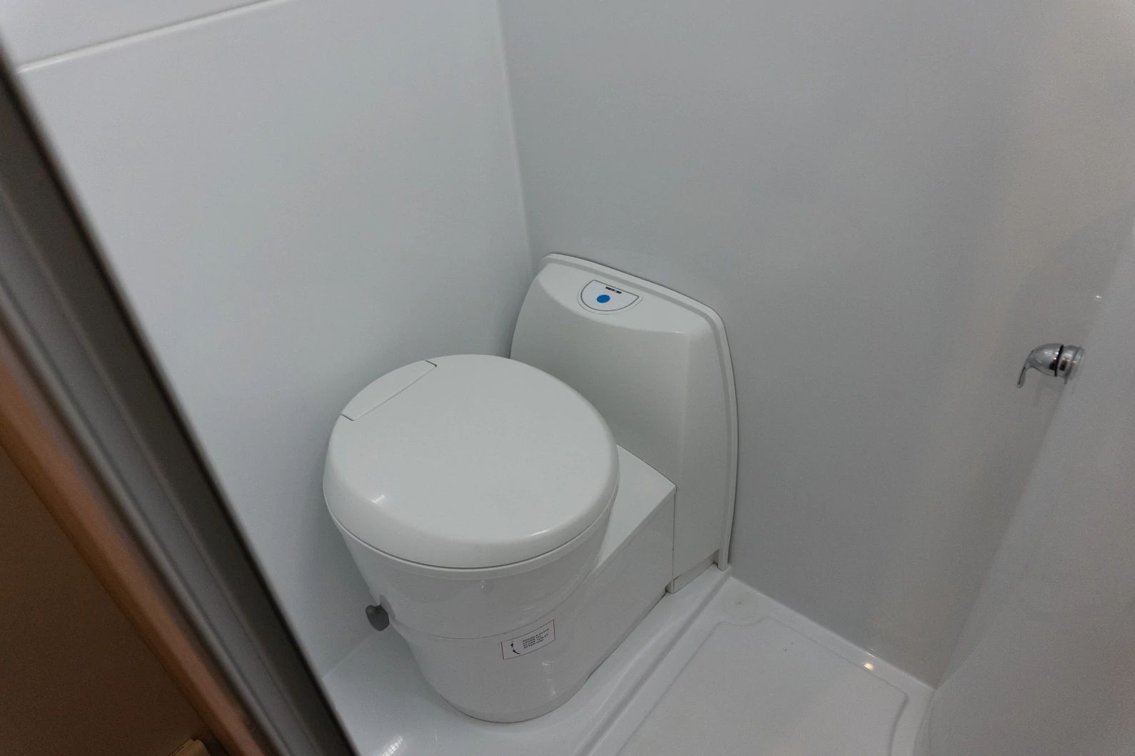 Compact white cassette toilet installed in a small campervan wet room cubicle.