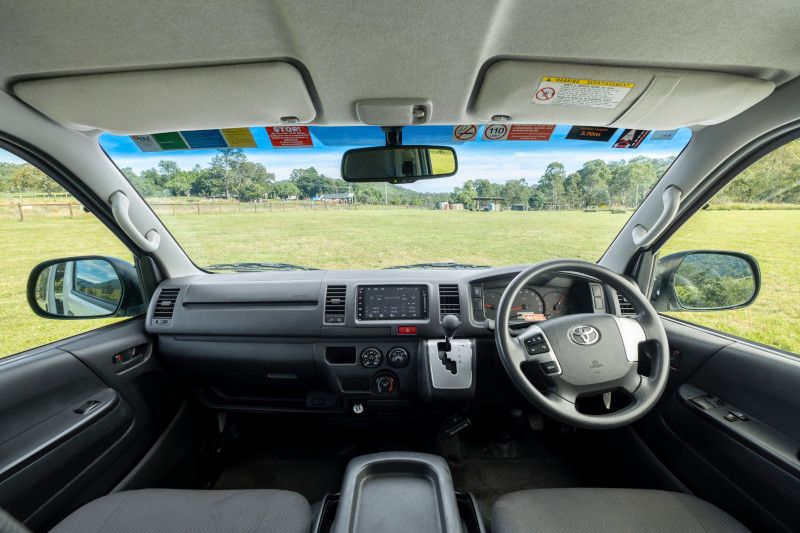 Right-hand drive dashboard interior of a Toyota campervan, looking out onto a grassy field.
