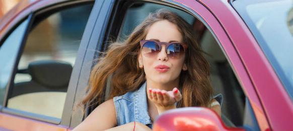 beautiful young brunette woman with long hair wearing sun glasses inside a car hire