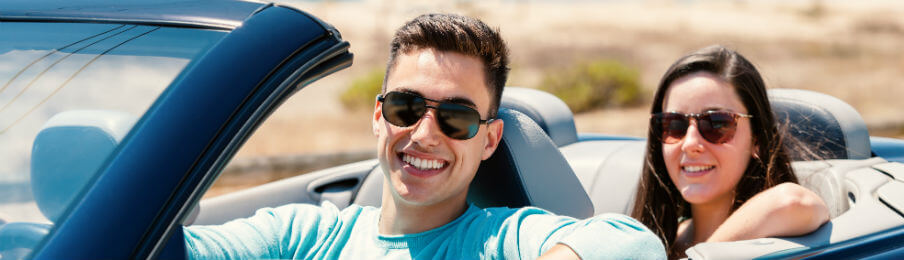 couple driving a rental car on a warm day