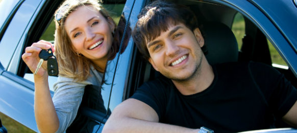 smiling couple posing inside their car rental in cambridge
