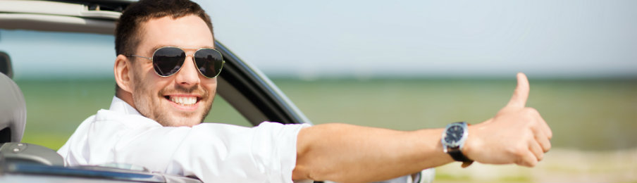 excited lad driving his car and showing a thumbs up sign