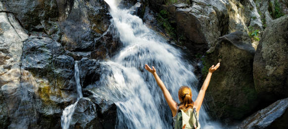 female hiker looking at waterfall