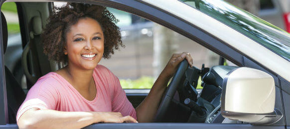 smiling female tourist with curly hair driving a rental car
