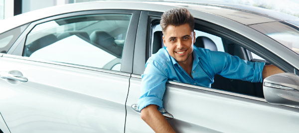 good looking man smiling while riding his new car