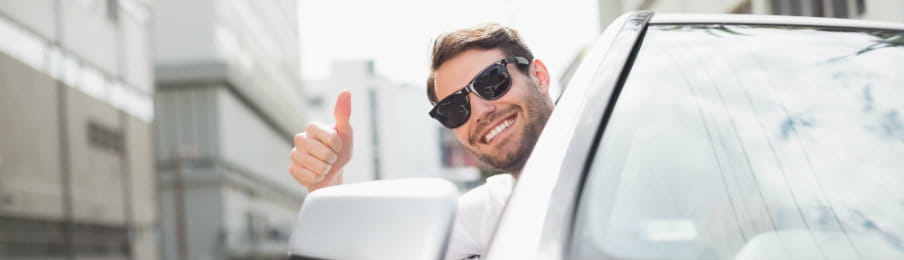 happy businessman in the driver’s seat showing a thumbs up