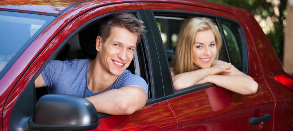 happy couple sitting inside the red car rental