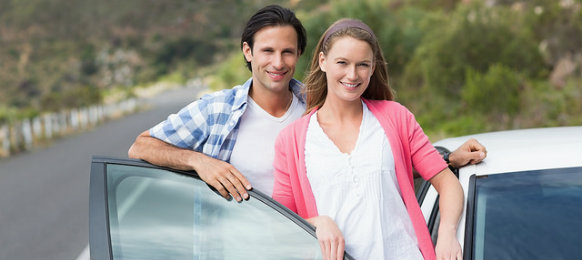happy couple standing beside their hire car