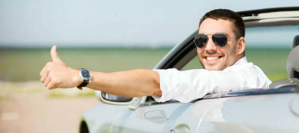 happy man driving a hire car and showing thumbs up