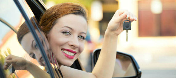 happy smiling young attractive woman sitting in her car hire