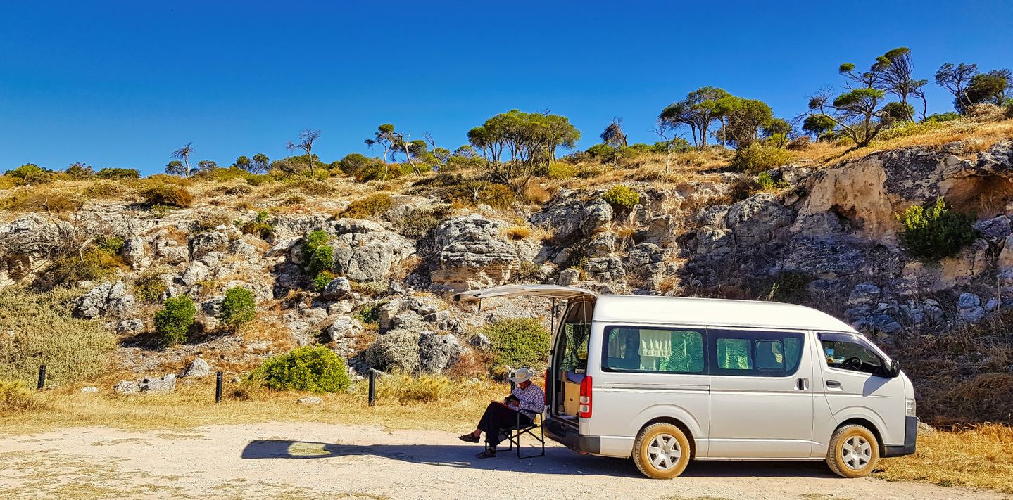 A campervan parked at a rocky hillside.
