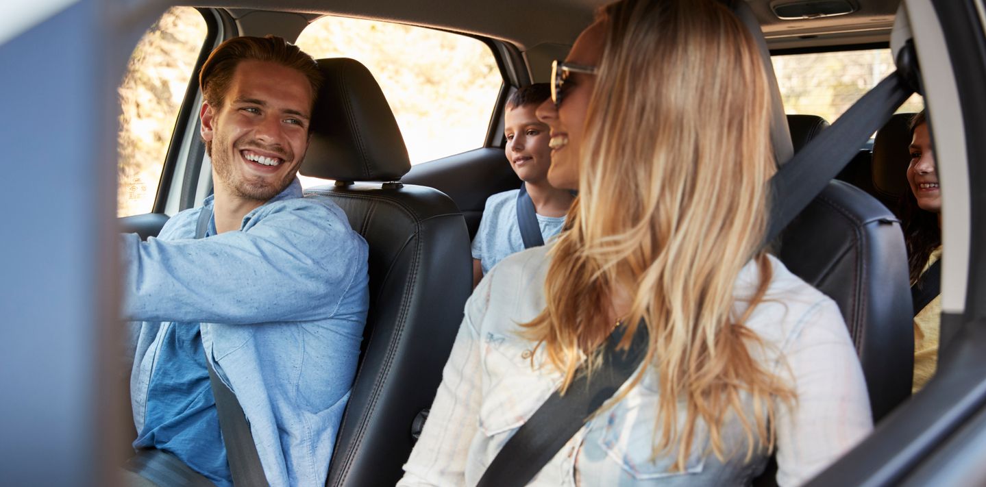 Family wearing seat belts in a car.