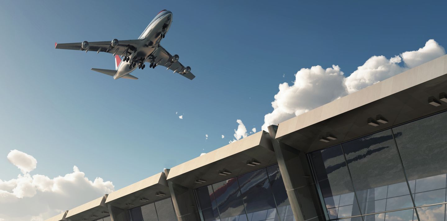 Aircraft taking off over a terminal building.