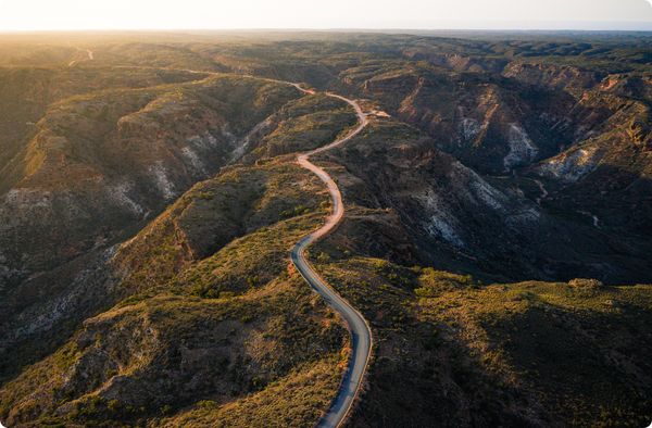 Aerial shot of a curving road through mountainous canyon landscape