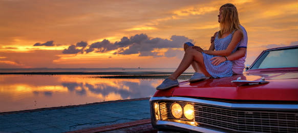 man and woman on their car rental watching a sunset