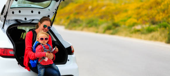 mother and little daughter travel by car in summer nature