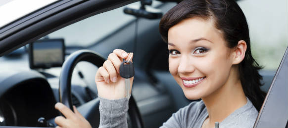 pretty asian female driver in a white car rental showing the car key