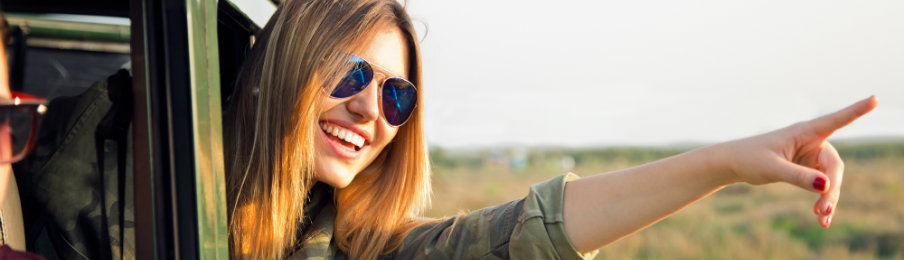 happy traveler pointing to something outside her rental vehicle