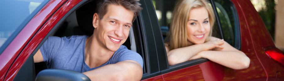 smiling couple inside a red car rental