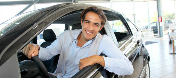 smiling man sitting at the steering wheel of his car rental