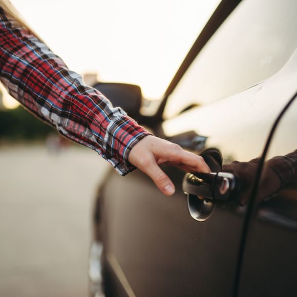A person holding a car door handle.