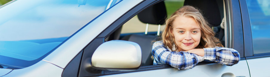 satisfied teenage girl sitting in a car rental