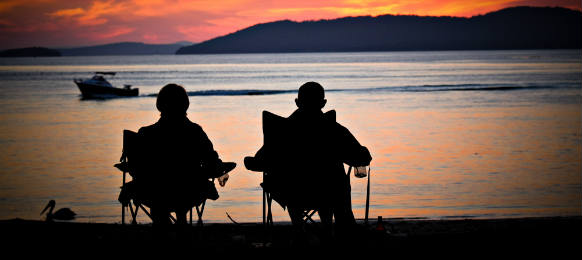 two friends silouhette straing at the sunset in the bay