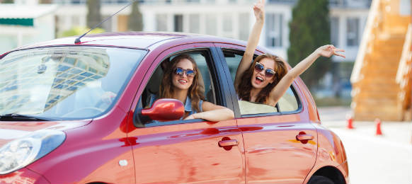 two happy girlfriends traveling with their car rental