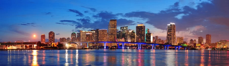 view of the urban skyscrapers and bridge over sea in miami taken at dusk