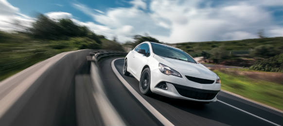 White car cornering in mountain road with speed blur