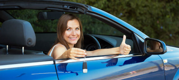 smiling woman giving thumbs up in a car hire