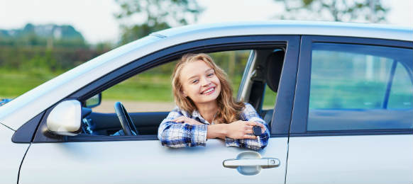 beautiful young driver looking out of the car rental window holding a key