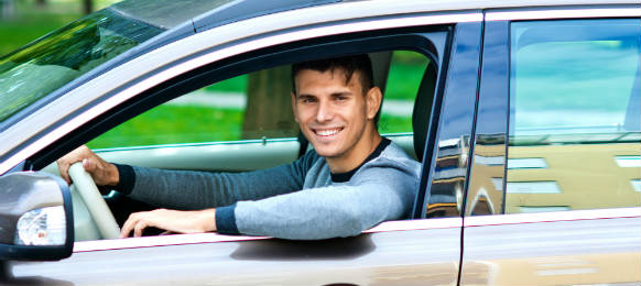 young man at driver seat of his car rental looking through window