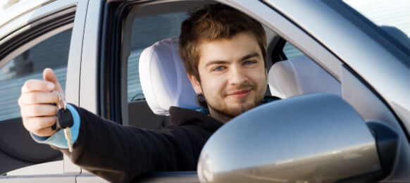 young man showing keys of car hire