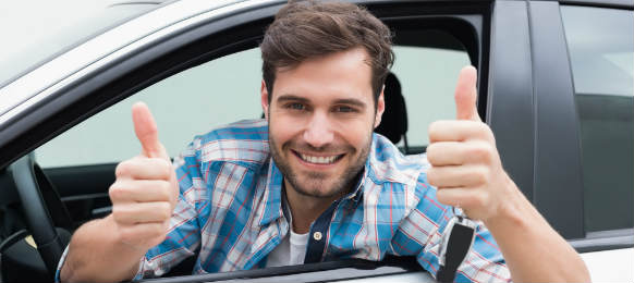 young man smiling and showing thumbs up inside the hire car
