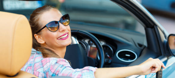 young pretty woman in sunglasses sitting in a car hire with the keys in hand