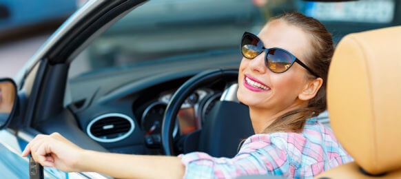 young pretty woman in sunglasses sitting in a car hire with the keys in hand
