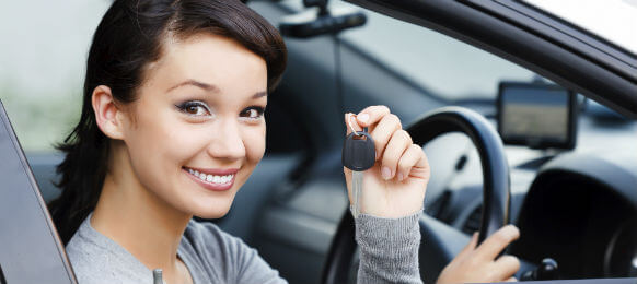young female traveler showing the key to her hire car