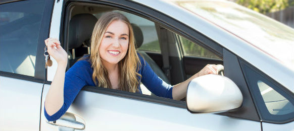 young woman sitting in her car hire holding keys