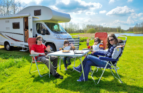 family enjoying a picnic beside their campervan