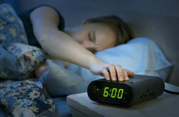 woman snoozing her alam clock